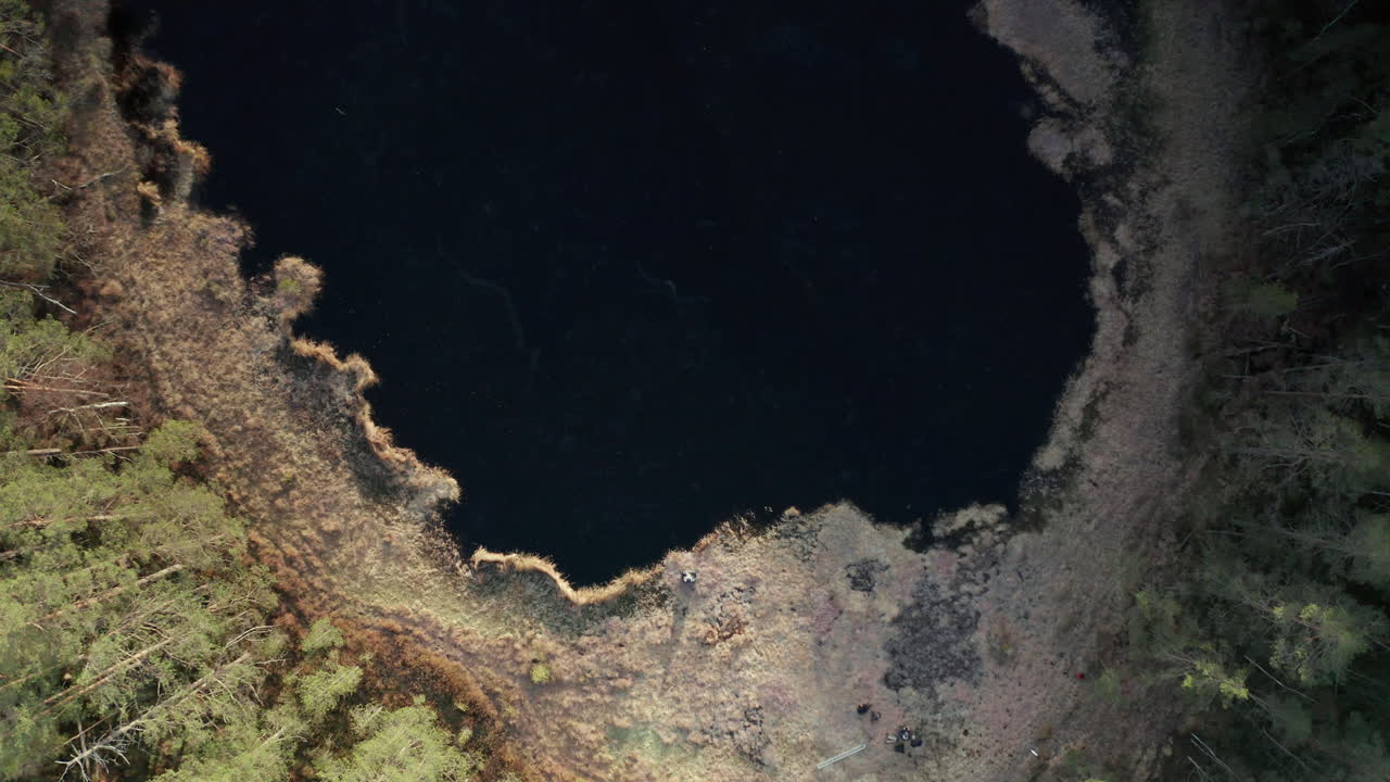 съемка с воздуха сверху вниз - купальщик сидит на берегу замерзшего озера