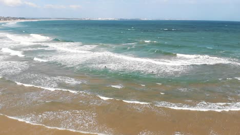 Waves-softly-coming-ashore-in-Lagos,-Algarve,-Portugal---Aerial-tilt-down-low-angle-shot