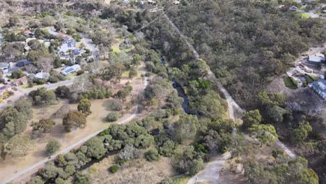 Drone-aerial-panning-up-over-a-town-with-a-river-system-and-lush-trees