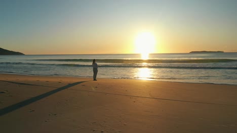 Woman-stands-alone-at-the-beach-contemplating-the-ocean