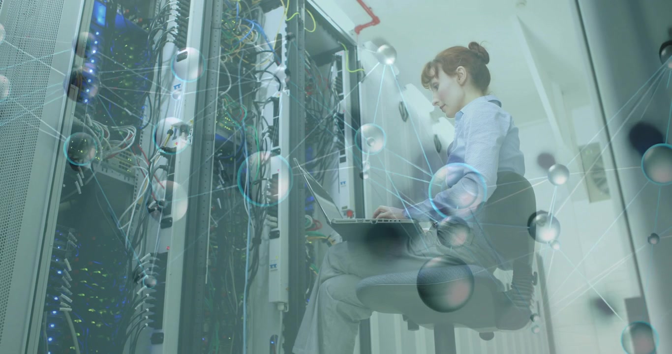 Technician powering laptop and running diagnostics in server aisle while spheres showing data flow