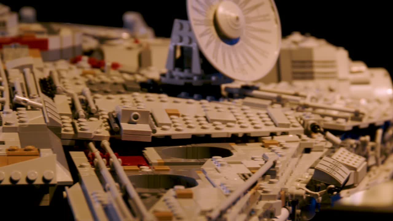 Slow, low angle pan right to left across LEGO Millennium Falcon ending on Han Solo and Chewbacca sat in cockpit