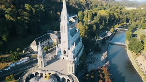 aerial establishing shot of the lourdes cathedral with tourists queueing outside