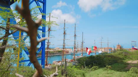 panorámica lenta que muestra una regata de grandes barcos amarrados a lo largo del río con un pueblo y un soporte estructural azul para un puente en curazao