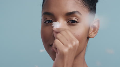 retrato de belleza de cerca hermosa mujer afroamericana tocando el rostro con plumas cayendo sobre la piel suave disfrutando del cuidado sensual de la piel acariciando suavemente la piel sana en cámara lenta