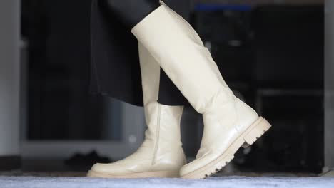 woman in a long skirt presents her high white boots