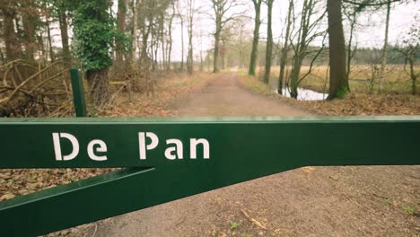 The-entrance-to-De-Pan-in-Cranendonck-during-winter,-showcasing-a-serene-path-through-the-natural-area-surrounded-by-bare-trees-and-a-quiet-landscape