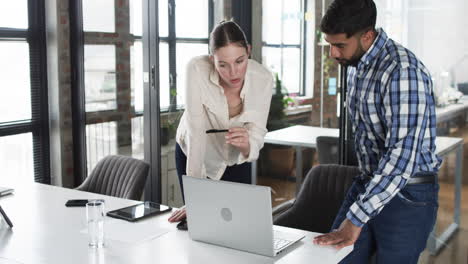 Young-Caucasian-woman-and-Asian-man-review-business-content-on-a-laptop-in-an-office