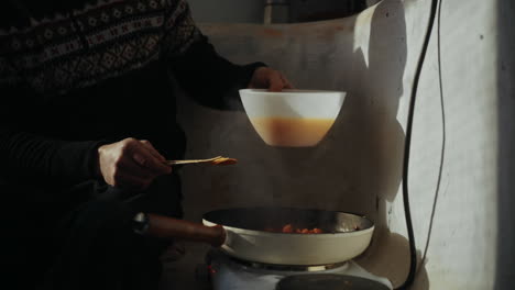 Worker-on-construction-site-pouring-eggs-into-preheated-pan-to-make-omelette-for-workers