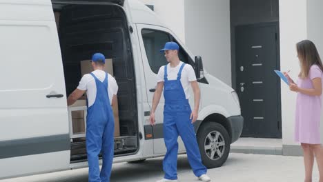 two young workers of removal company are loading boxes and furniture into a minibus