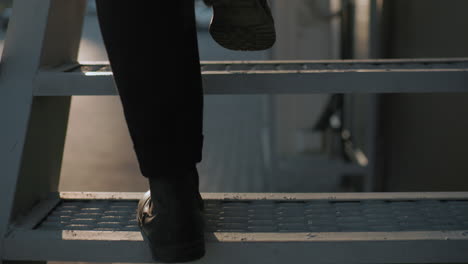 back leg view man black shoe and trouser climbing staircase carefully with warm soft light reflecting off interlocked stone path, slow deliberate step, focus on movement