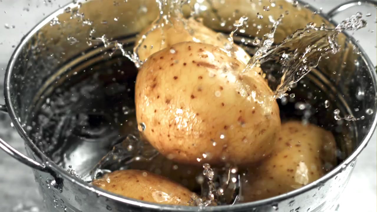 Patate fresche che cadono nell'acqua con schizzi al rallentatore