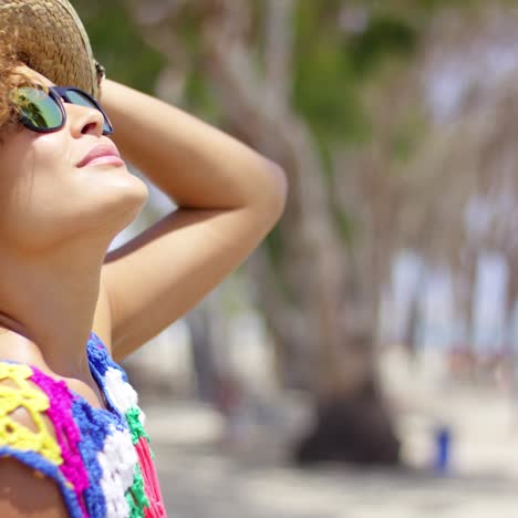 mujer con gafas de sol y sombrero afuera mirando hacia arriba