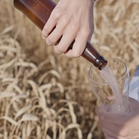 man pours beer from a bottle into a glass