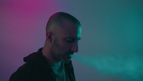 middle age depressed man smoking marijuana in the corner of a colorful wall during a party