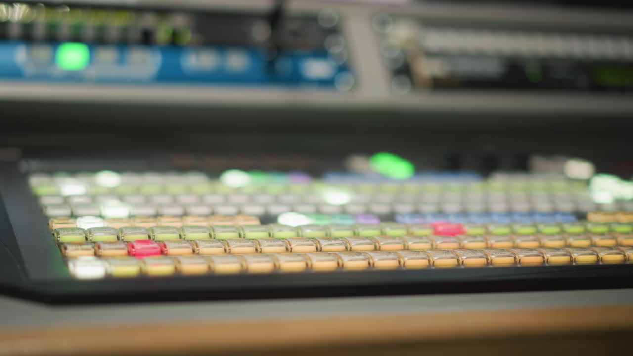 Close-up of hand operating television broadcast control panel with colorful buttons, used in video editing, camera switching, and live broadcast production. Technology and media control setup