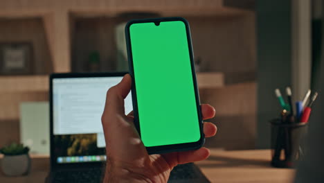 guy watching green screen smartphone social media sitting desk laptop closeup.