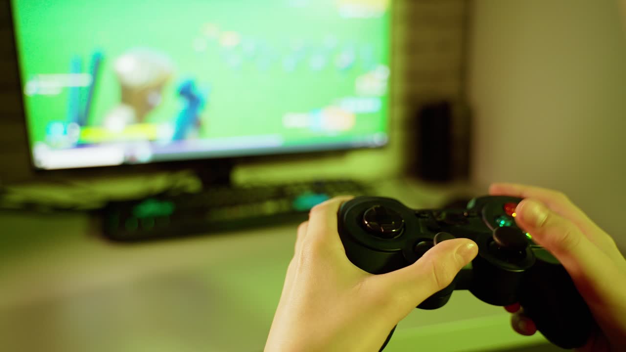 Boy uses joystick to play video game on Play Station. The console in gamer's hands during game time in front of the screen. Close-up.