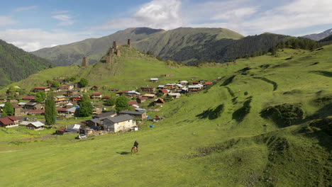 Rotating-drone-shot-of-man-riding-a-horse-in-upper-Omalo,-Tusheti-Georgia