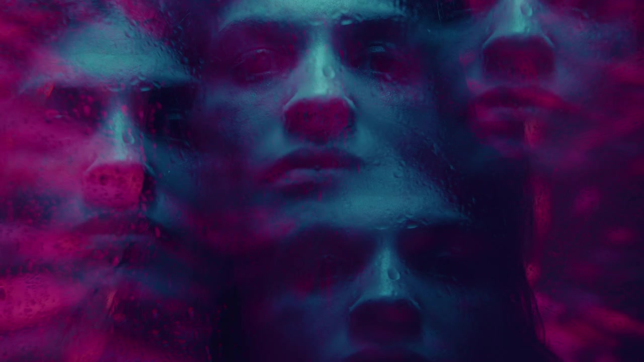 Kaleidoskopický efekt smutné dívky za mokrým oknem v neonovém světle