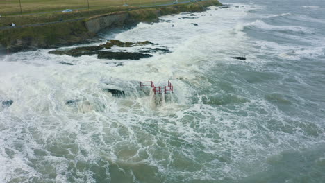 Aerial-view-of-waves-crashing-against-rocks-along-the-coastline-during-a-storm