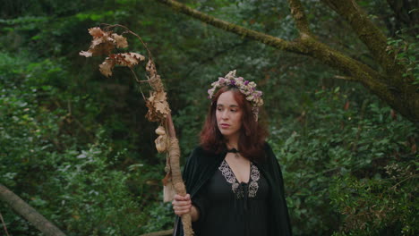 young druid girl holding a wooden staff walks in a forest medium shot