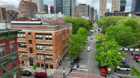 Aerial-approach-of-American-flag-waving-in-breeze-at-urban-city-school-in-NYC