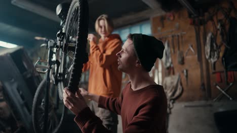 dad and son work in the garage, they check if the chain on the bike is working