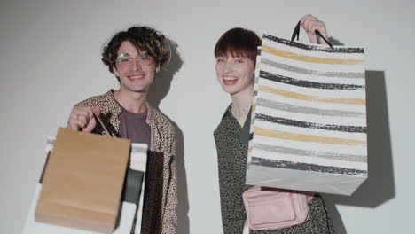 young happy girl and boy posing with shopping bags in studio