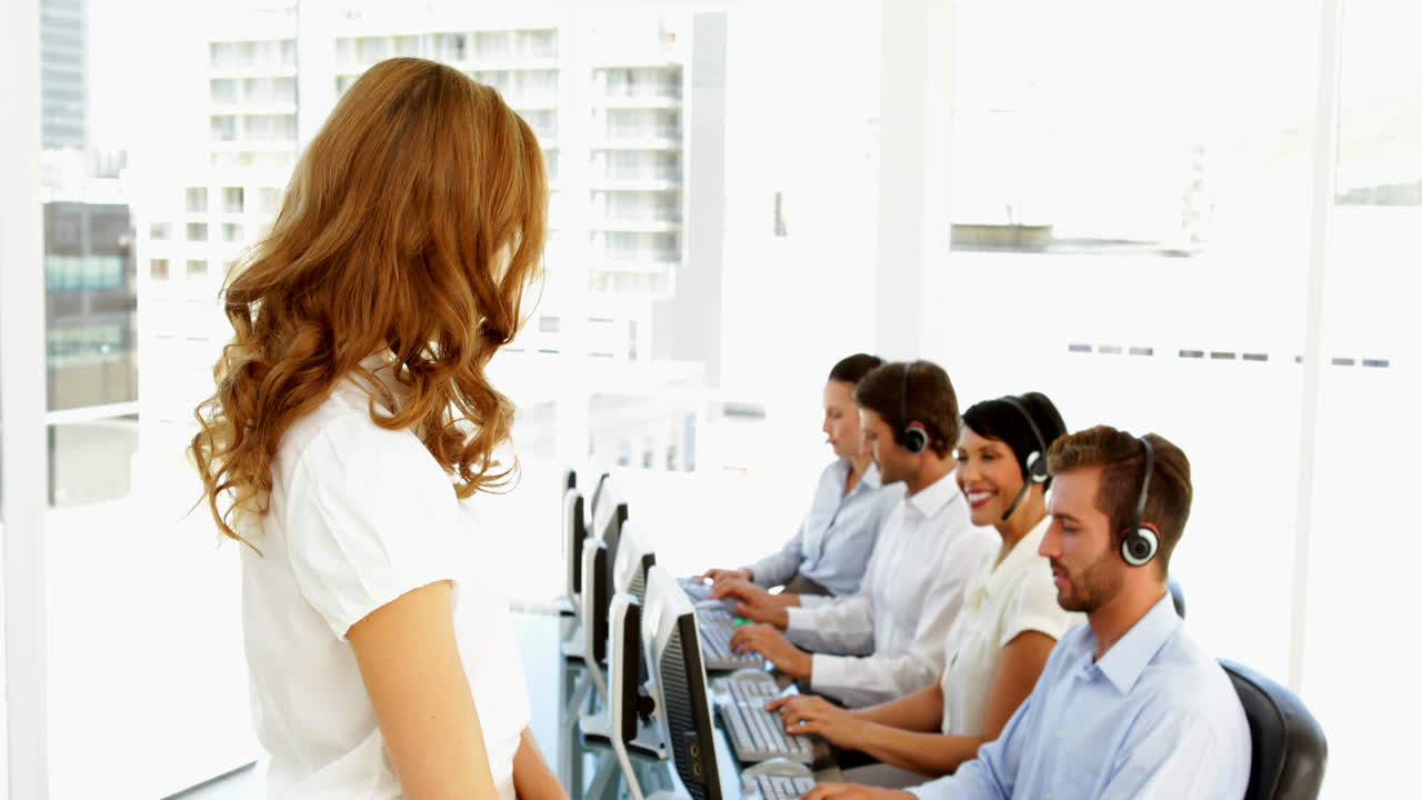 gerente haciendo una señal de ok frente a los empleados del centro de llamadas