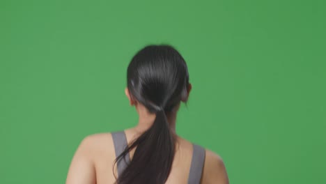 woman in grey sports bra, back view, on green screen