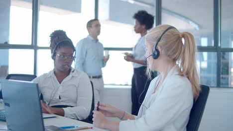 two call center operators in headsets sitting together