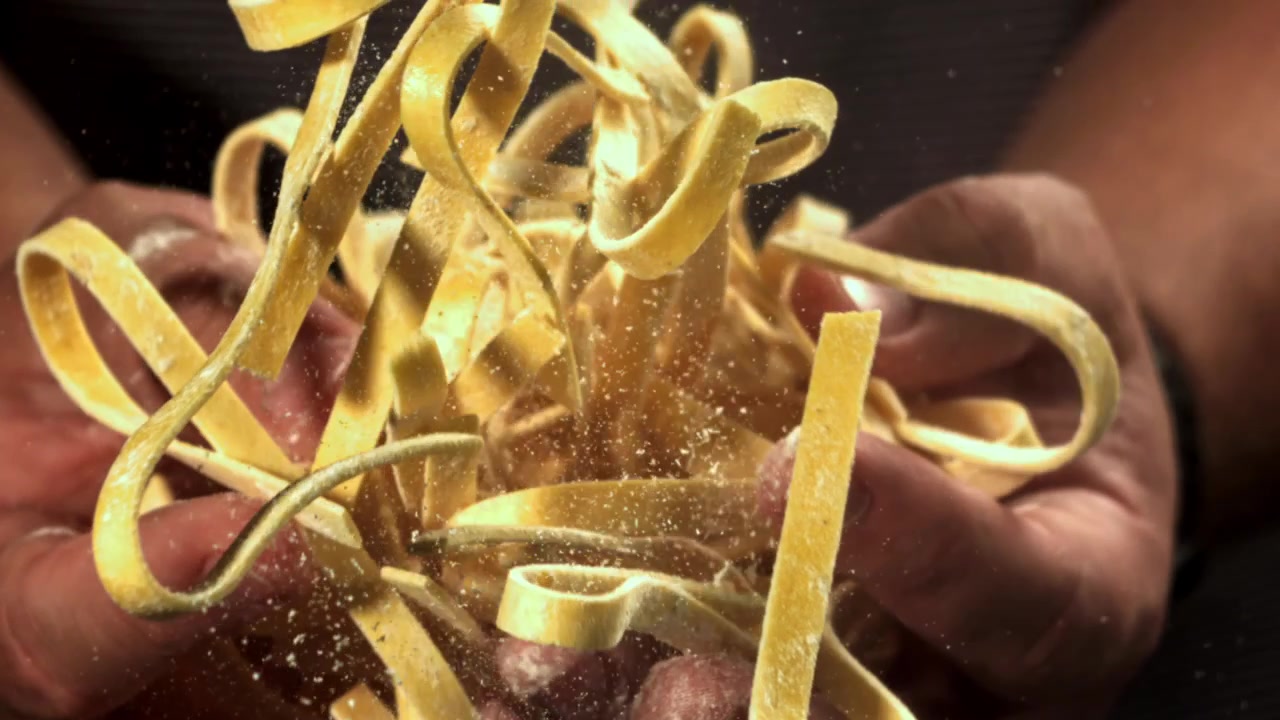 Farina che cade al rallentatore su pasta fresca fatta in casa nelle mani