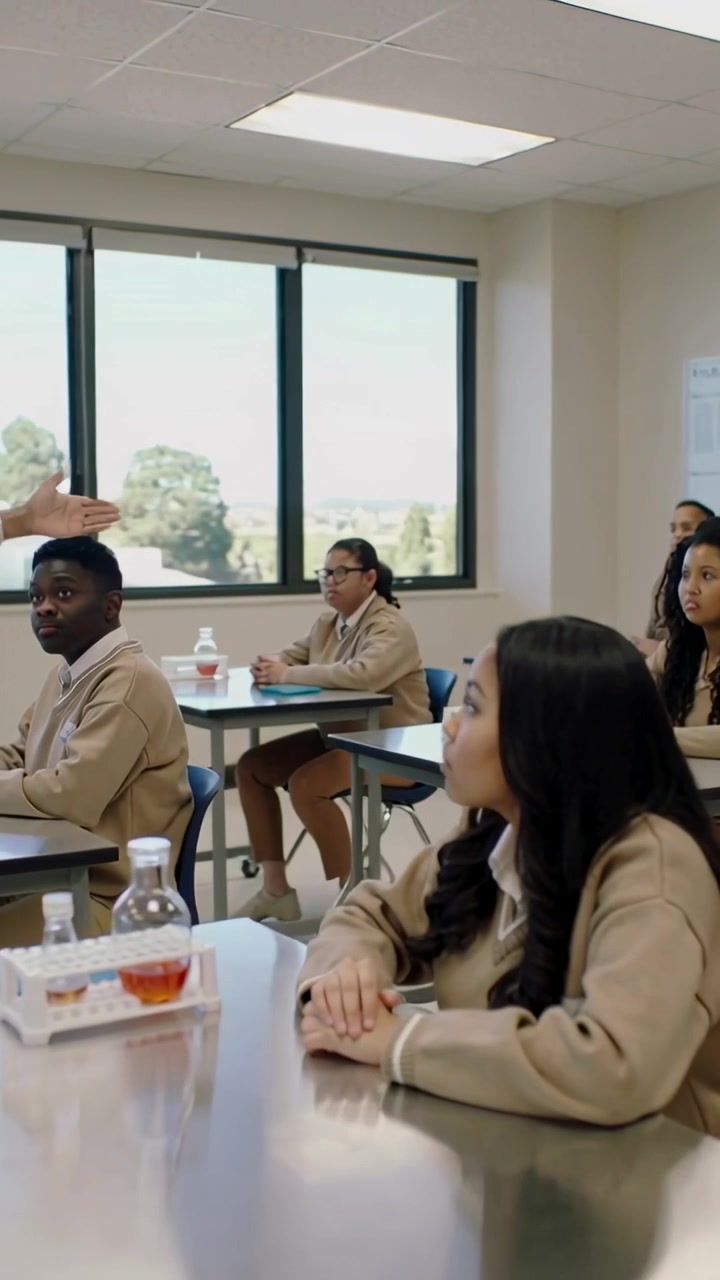 Vertical video: Turning curly student in uniform listening to teacher gesturing in lab, with flask