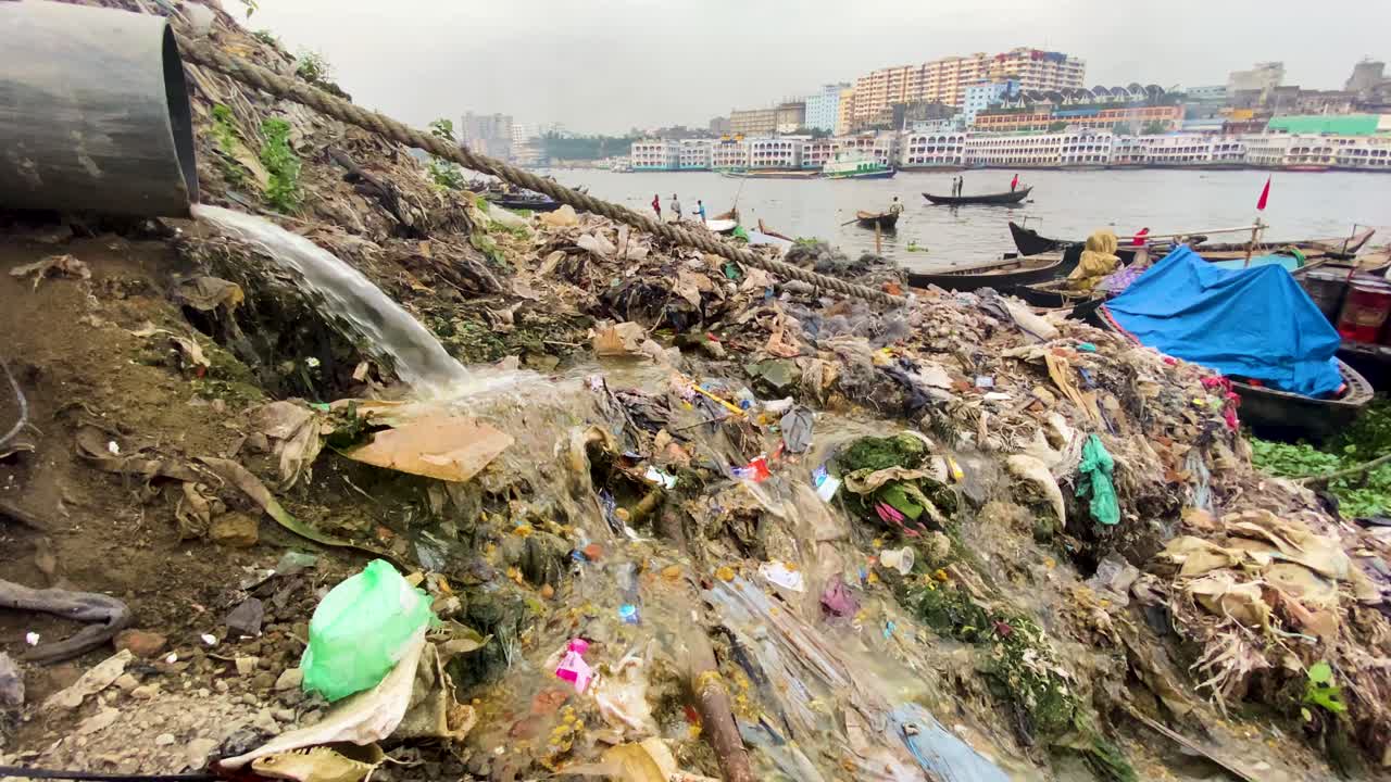Dirty sewage water running down a huge hill of trash, river pollution in the Buruganga river, Dhaka, Bangladesh, slow motion