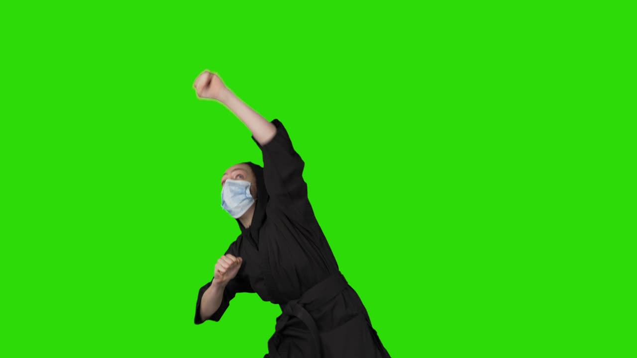Video of struggling woman in black costume ninja on green isolated background