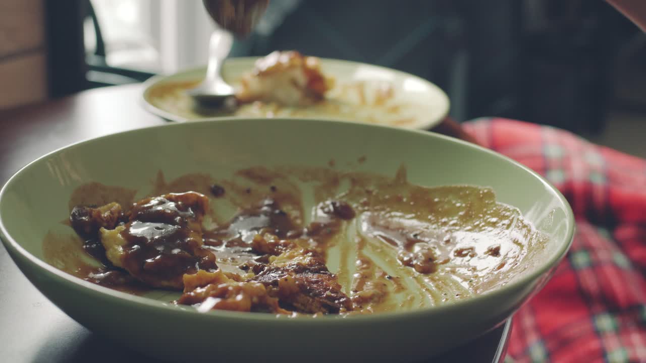 Scooping And Trying To Finish Off Food From A Plate On The Table - closeup shot