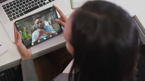 biracial businesswoman using tablet for video call with african american business colleague