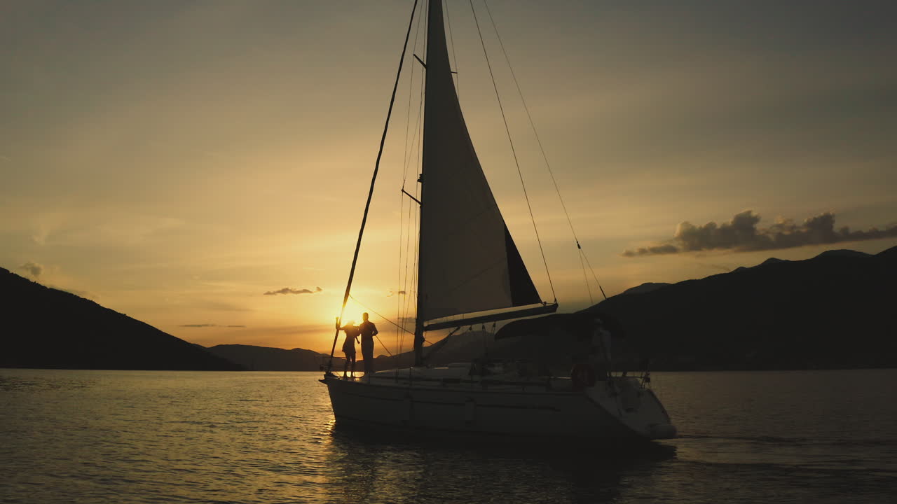 Casal Apreciando um Cruzeiro de Vela ao Pôr do Sol