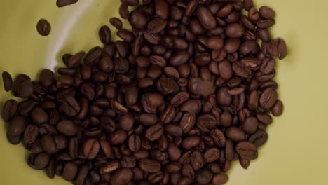 coffee beans falling into a green bowl