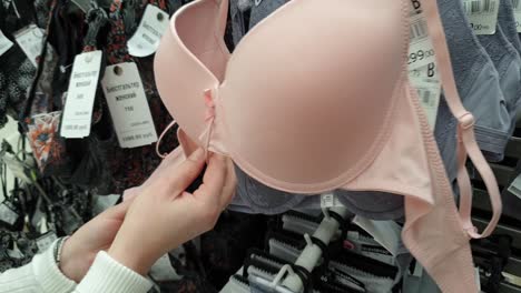 una mujer haciendo compras en el centro comercial, eligiendo ropa interior, sostén.