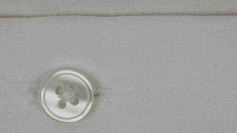 botón de cuatro agujeros en una camisa de algodón blanco liso