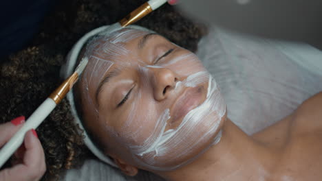 cosmetologist hands applying mask for moisturising beauty procedure closeup.