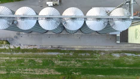 top down view of grain silos on a green field - drone shot