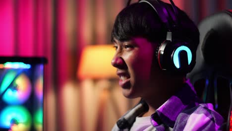 close up of excited asian teen boy gamer playing video game on computer