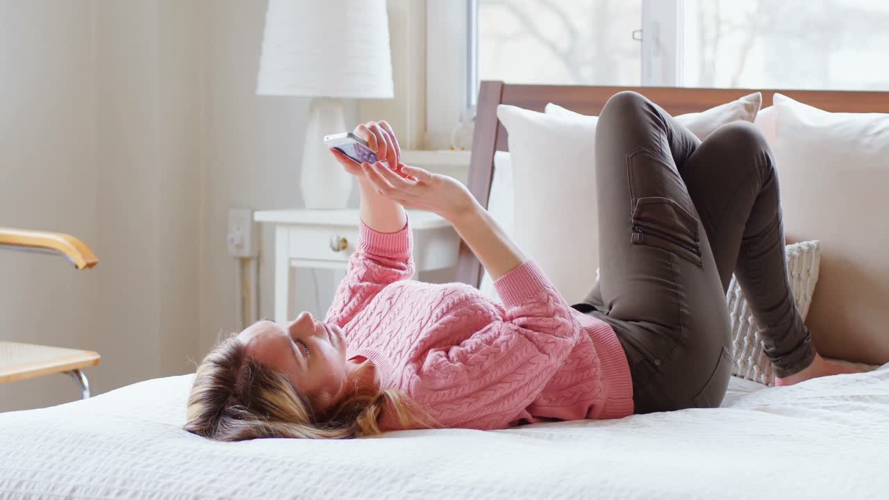 침대 4k에 휴대 전화를 사용하는 아름다운 여성