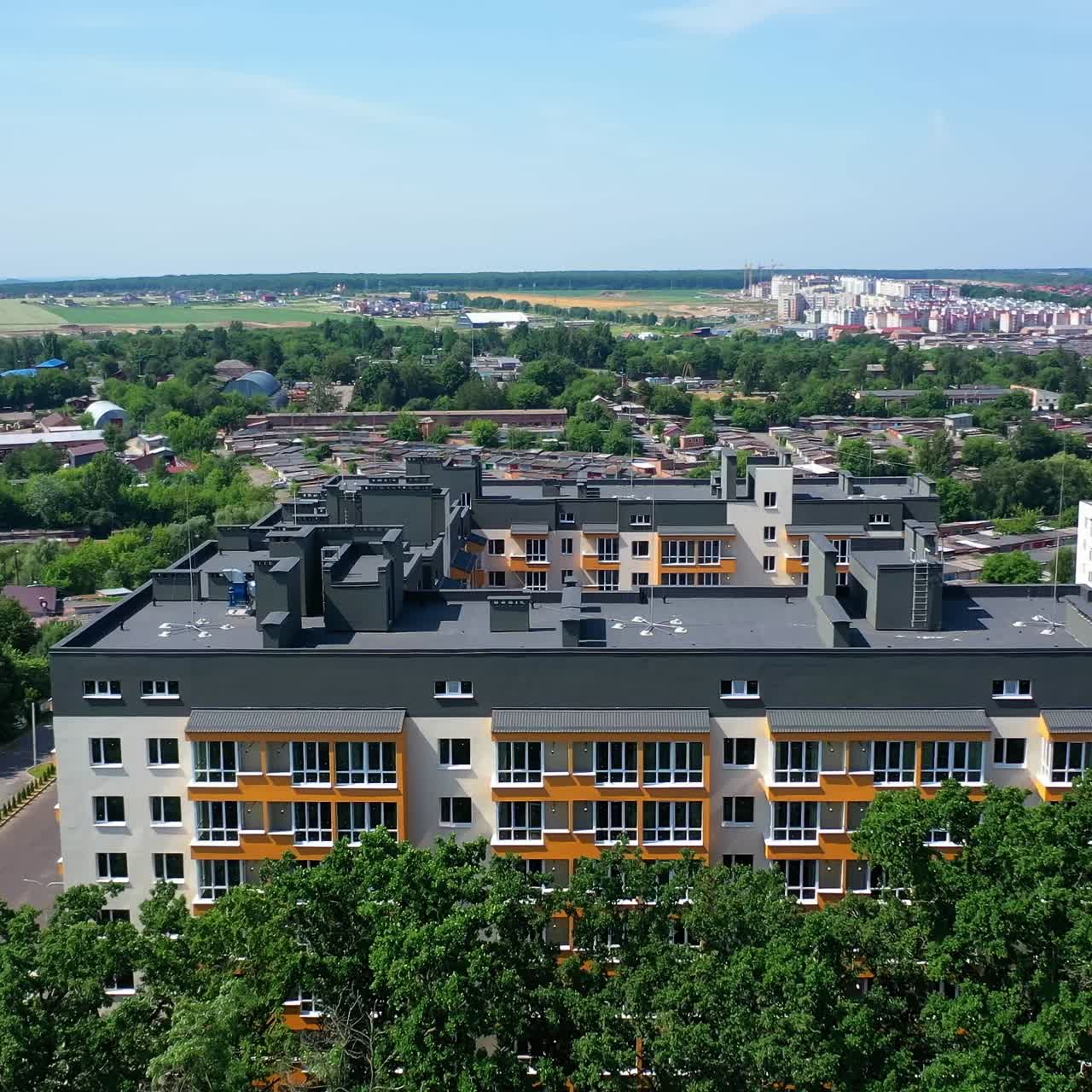 New apartment building on urban background. Block of flats among green trees. Modern high-rise building in the city. Aerial view