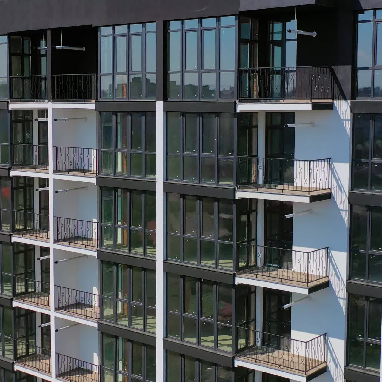 Newly built urban architecture. Exterior of residential building in the city. Modern building with tall glass windows and balconies.