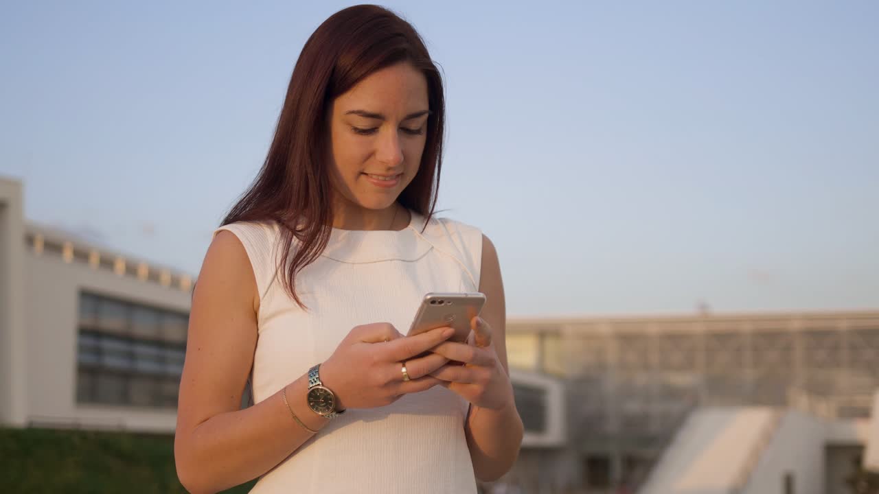 una joven sonriente enviando mensajes en su teléfono inteligente.