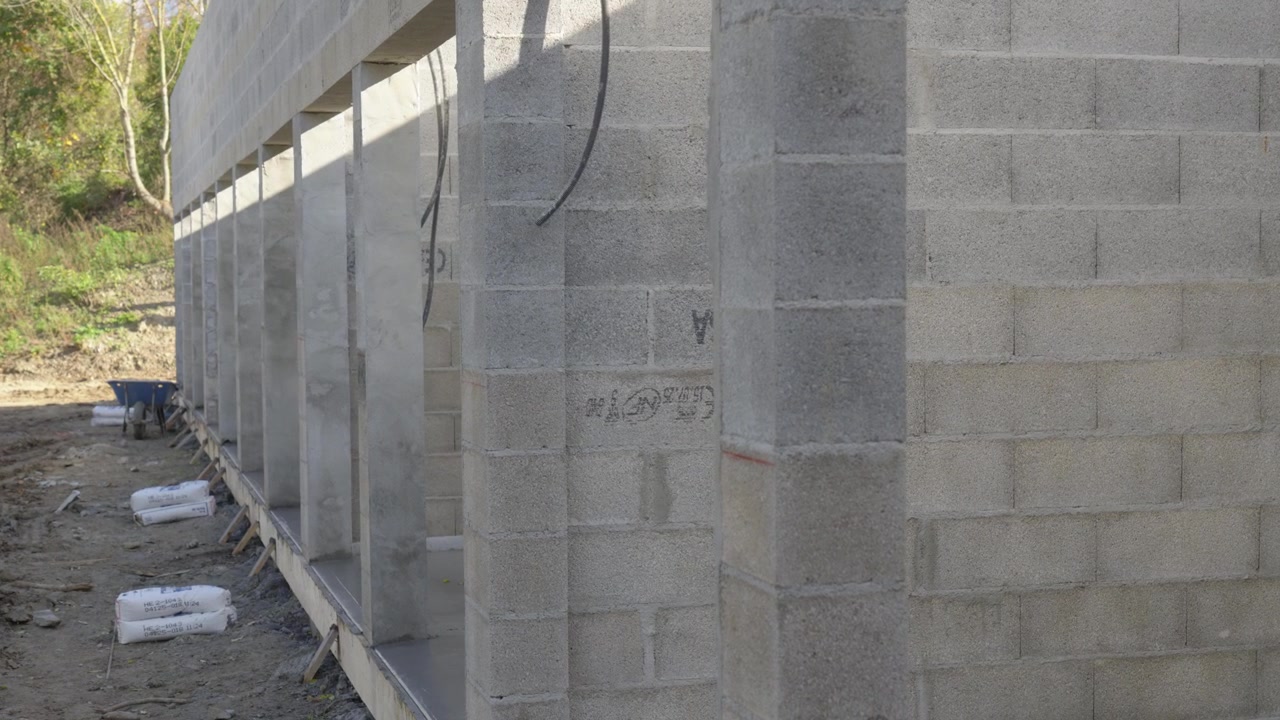 Muro di blocchi di cemento in costruzione in un cantiere edile illuminato dalla luce naturale.